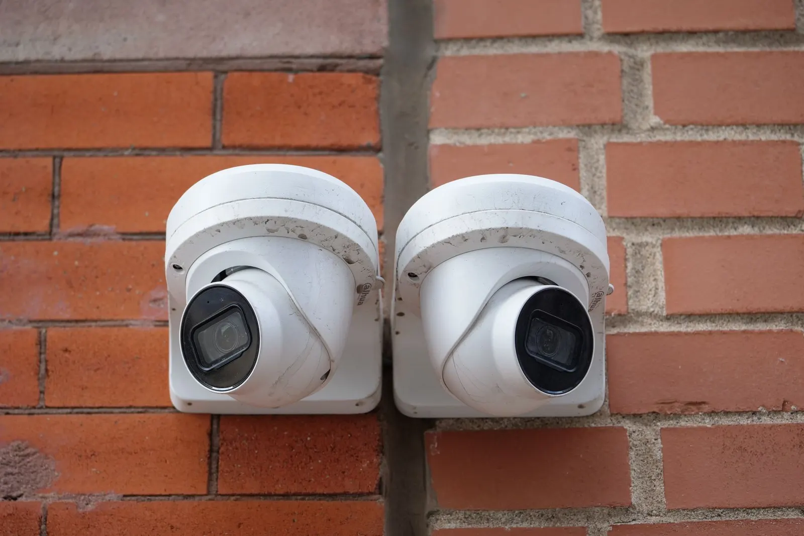 Két fehér dóm kamera egy téglafalú ház sarkán